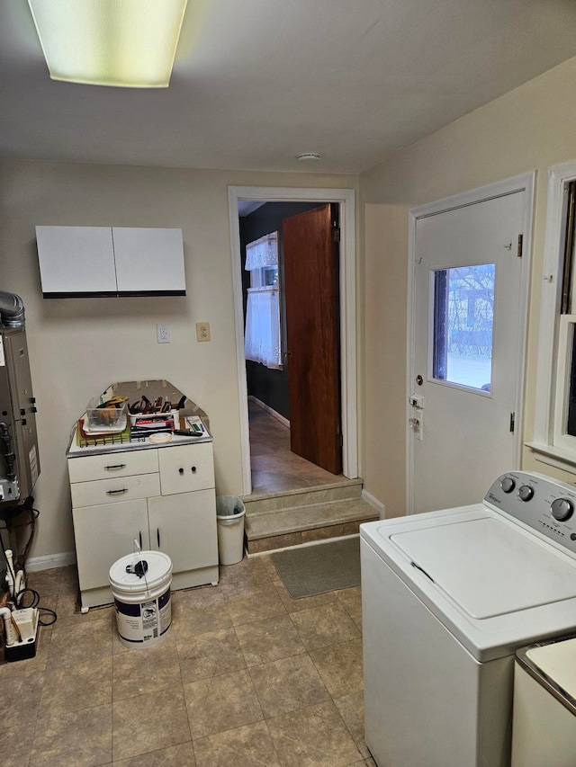 laundry room featuring washer / dryer, cabinet space, and baseboards