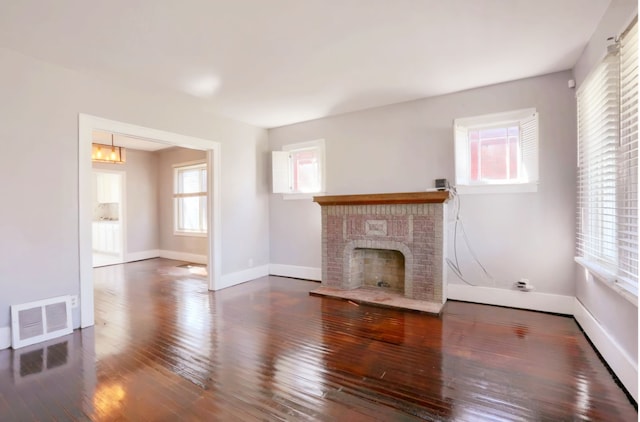 unfurnished living room featuring a brick fireplace and dark hardwood / wood-style flooring