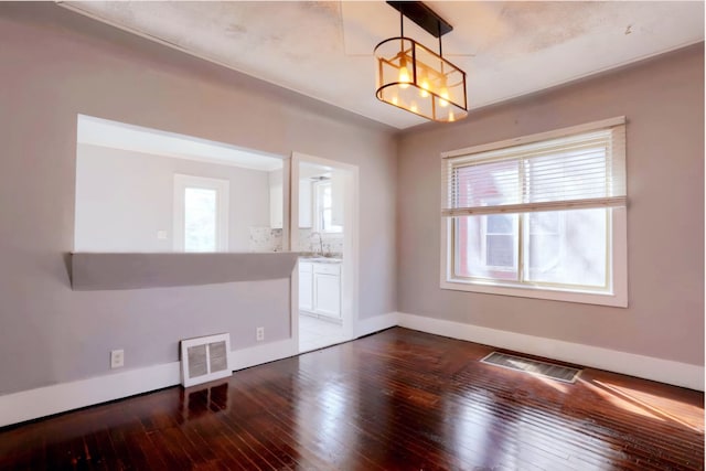 spare room with a healthy amount of sunlight, visible vents, and dark wood-style flooring