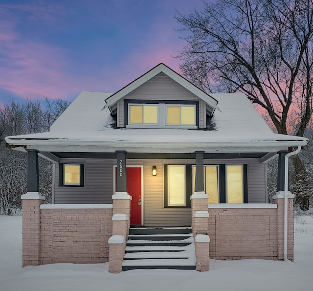 bungalow-style home with a porch and brick siding