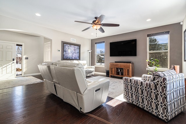 living area with a ceiling fan, baseboards, arched walkways, and dark wood-type flooring