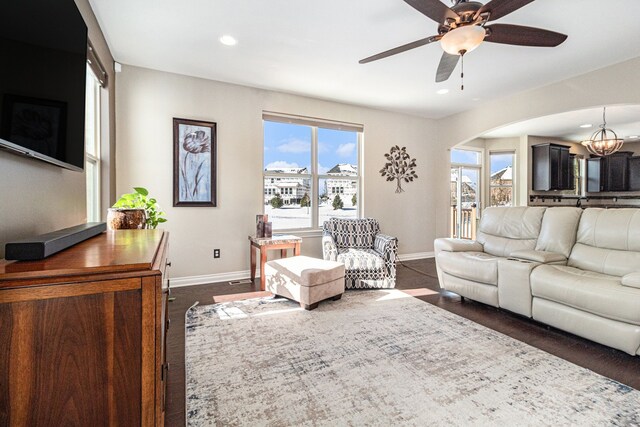 living area featuring recessed lighting, baseboards, arched walkways, and ceiling fan with notable chandelier