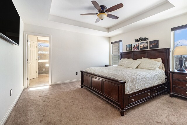 bedroom featuring a tray ceiling, light carpet, and baseboards