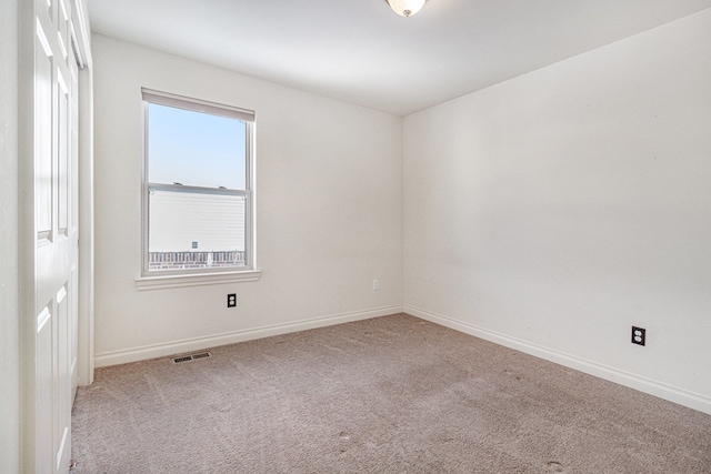 carpeted empty room featuring visible vents and baseboards