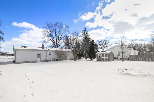 snow covered rear of property featuring a shed