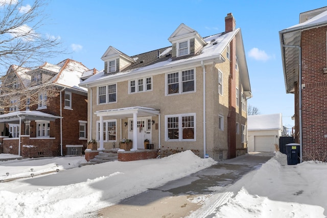 traditional style home with a garage, a chimney, an outbuilding, and stucco siding