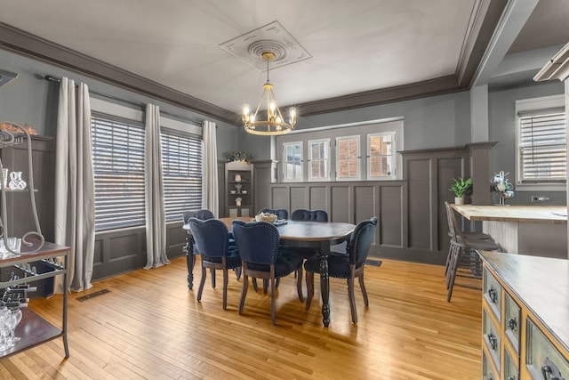 dining space with light wood finished floors, a healthy amount of sunlight, visible vents, and crown molding