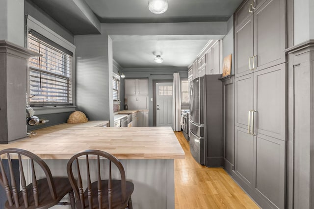 kitchen with a peninsula, light wood finished floors, a wealth of natural light, and a kitchen breakfast bar