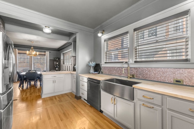 kitchen with butcher block countertops, black dishwasher, decorative light fixtures, and a sink