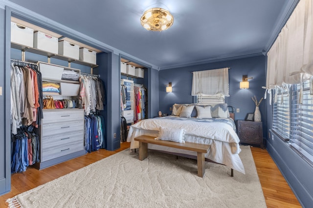 bedroom featuring multiple closets, crown molding, and wood finished floors