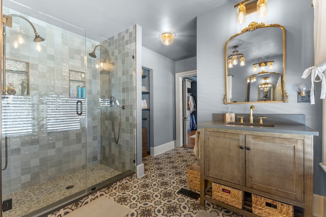 bathroom featuring tiled shower, tile patterned flooring, vanity, and baseboards