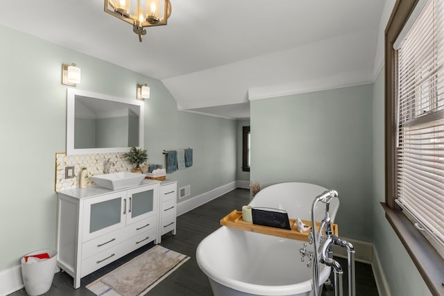 bathroom featuring lofted ceiling, a soaking tub, visible vents, vanity, and baseboards