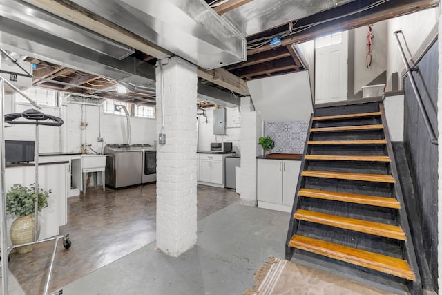 basement with electric panel, a sink, stairway, and separate washer and dryer