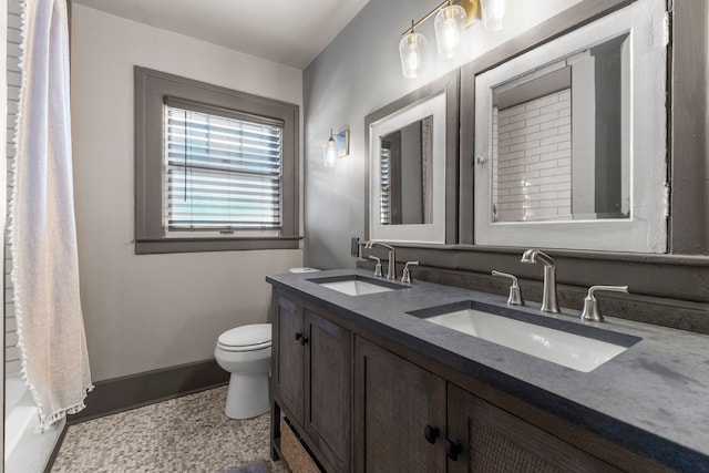 full bathroom with double vanity, baseboards, toilet, and a sink