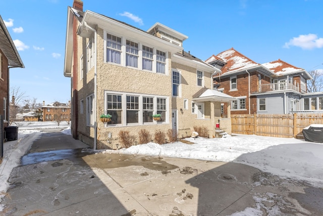 view of front of home featuring a chimney, fence, and stucco siding