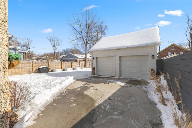 snow covered garage with a garage and fence