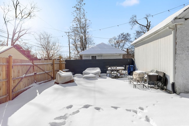 yard layered in snow featuring a fenced backyard and outdoor dining area