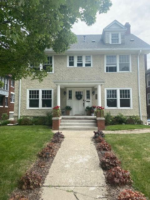 view of front facade with a front yard and a chimney