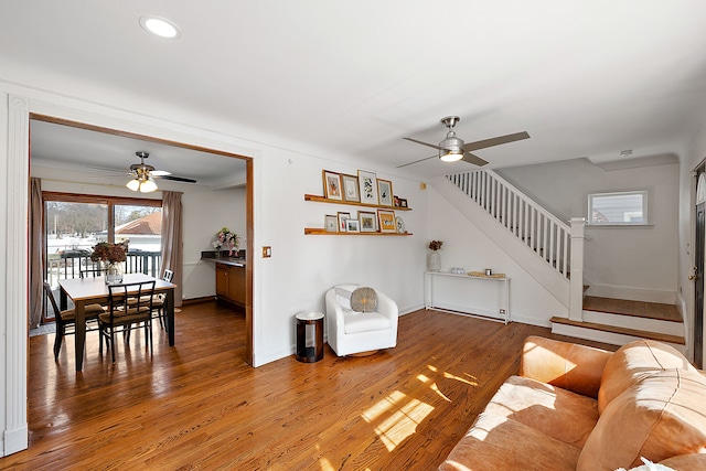 living room featuring baseboards, stairway, ceiling fan, and wood finished floors