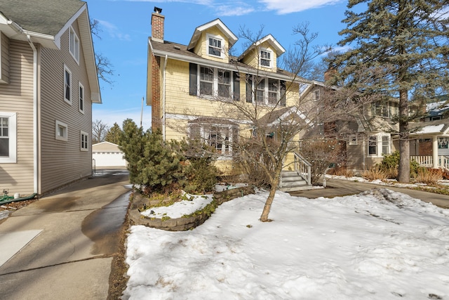 american foursquare style home featuring an outbuilding, a detached garage, and a chimney