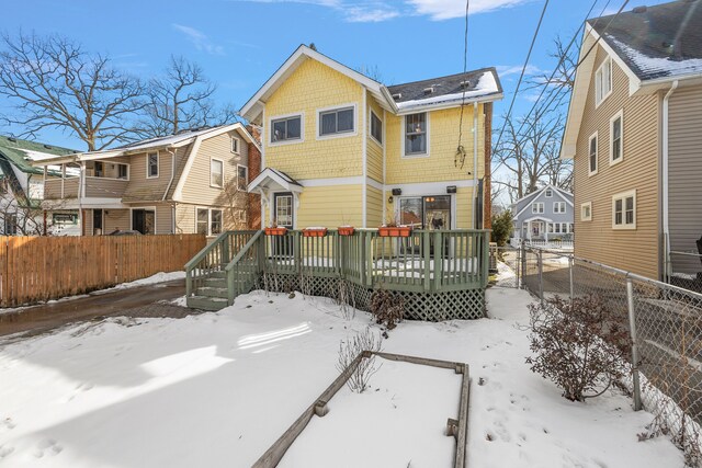 snow covered back of property with fence private yard, a residential view, and a wooden deck