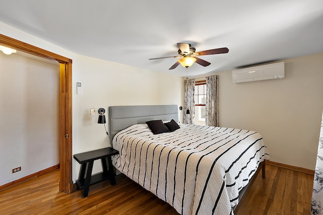 bedroom with a wall unit AC, ceiling fan, baseboards, and dark wood finished floors