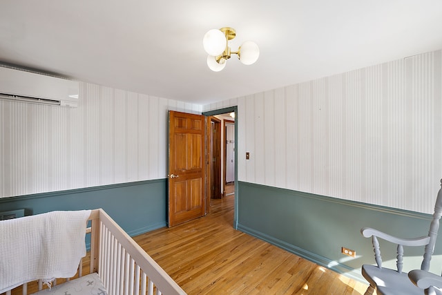 bedroom with wood finished floors and a wall mounted AC