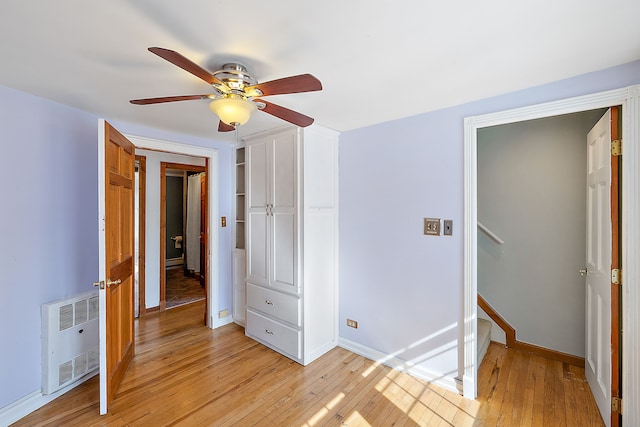 unfurnished bedroom with ceiling fan, radiator, light wood-style flooring, and baseboards