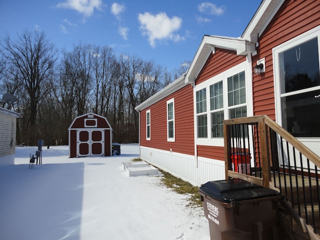 view of snowy exterior with a shed