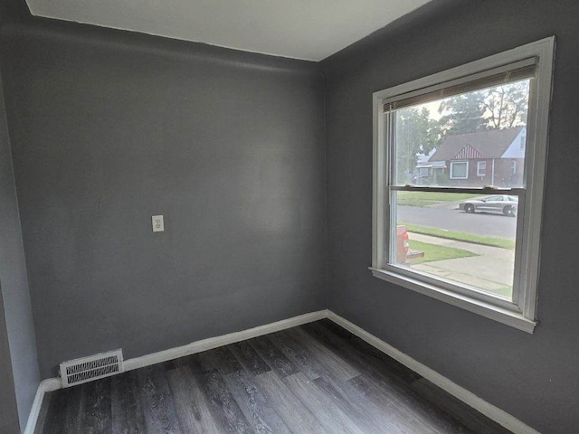 spare room featuring a healthy amount of sunlight, visible vents, baseboards, and wood finished floors