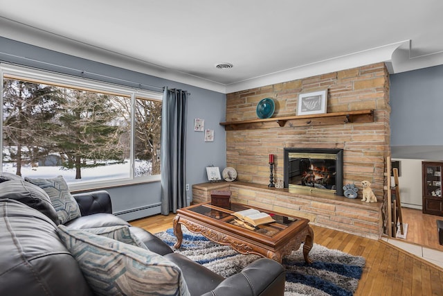 living room featuring baseboard heating, a fireplace, and hardwood / wood-style floors