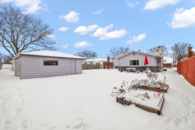 snow covered property featuring fence and an outdoor structure