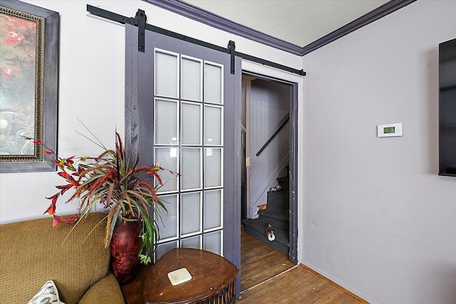 interior space featuring a barn door, stairway, wood finished floors, and crown molding