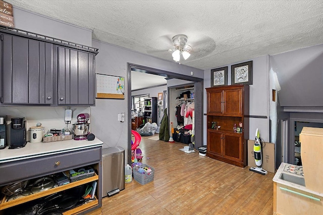 kitchen featuring light wood-type flooring, a ceiling fan, light countertops, and a textured ceiling