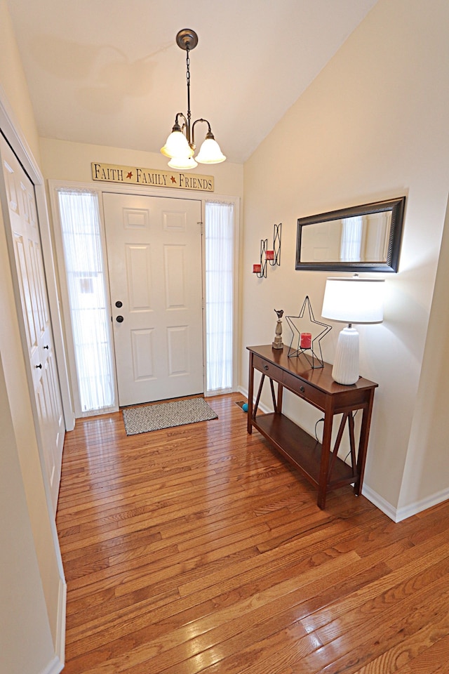 entrance foyer featuring an inviting chandelier, vaulted ceiling, and wood-type flooring