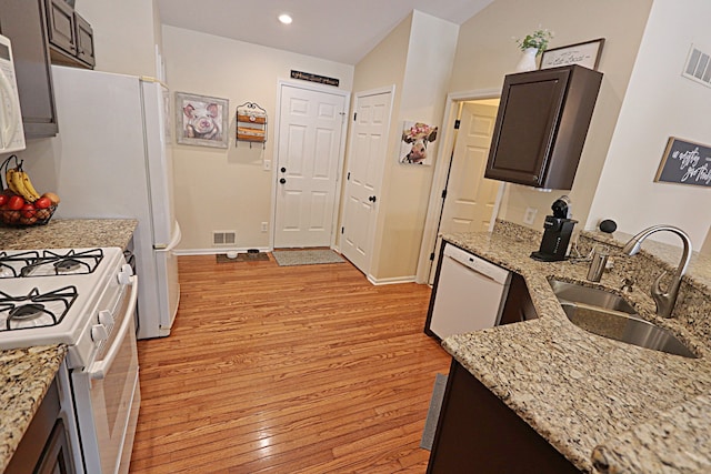 kitchen with white appliances, dark brown cabinetry, sink, and light hardwood / wood-style flooring