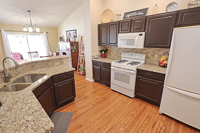 kitchen featuring sink, white appliances, dark brown cabinets, and decorative light fixtures