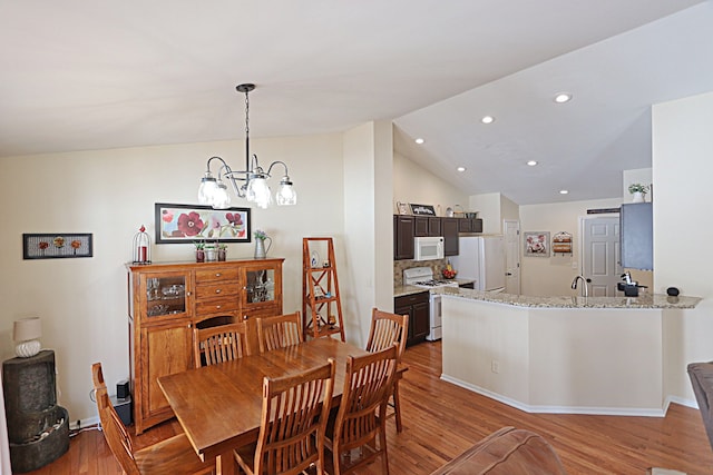 dining space with light hardwood / wood-style flooring, a chandelier, and vaulted ceiling