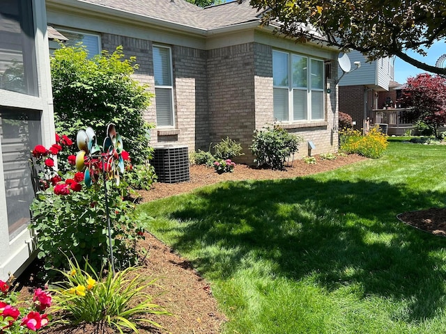 view of side of home featuring central AC unit and a lawn