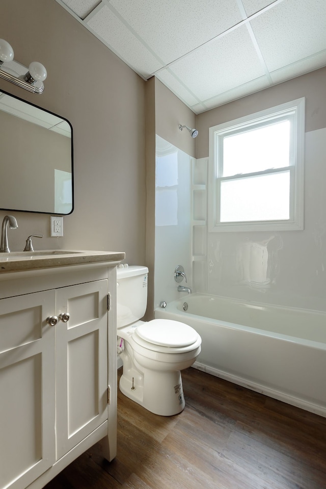 full bathroom with hardwood / wood-style flooring, toilet, shower / bathing tub combination, a paneled ceiling, and vanity