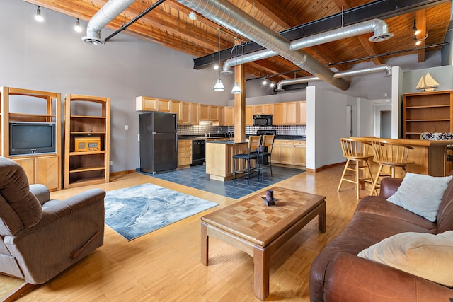 living area with a towering ceiling, light wood finished floors, wood ceiling, and rail lighting