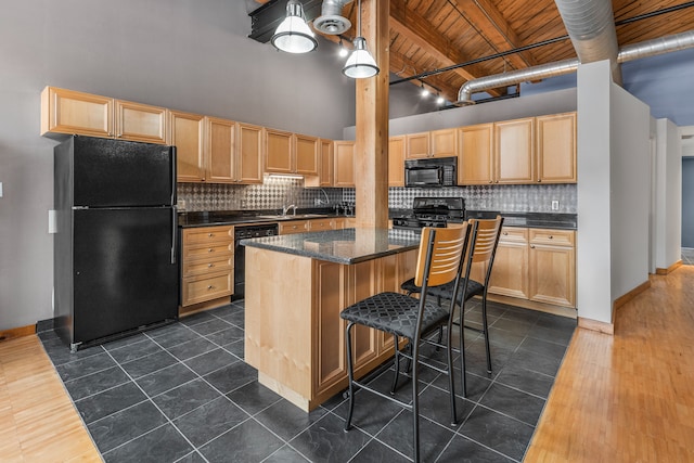 kitchen featuring wooden ceiling, a high ceiling, a kitchen island, light brown cabinetry, and black appliances