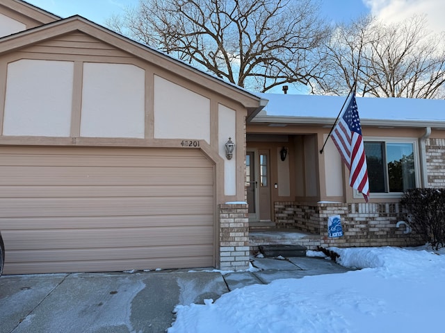 view of front of house with a garage, stone siding, and stucco siding