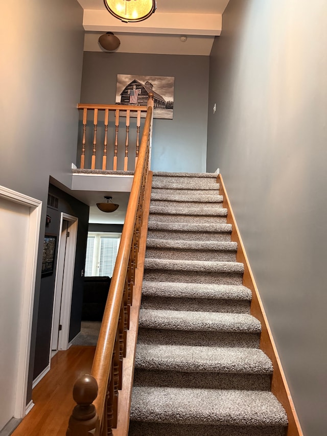 staircase with a high ceiling, baseboards, and wood finished floors