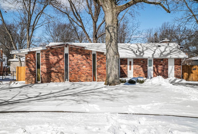 snow covered property with fence and brick siding