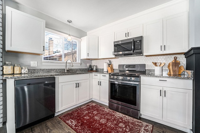 kitchen with a sink, dark stone counters, white cabinetry, and stainless steel appliances