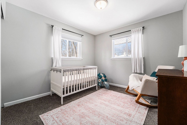 bedroom featuring baseboards, dark colored carpet, and a nursery area