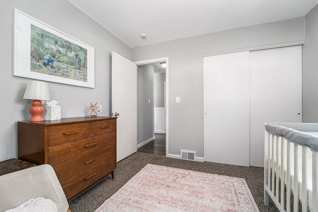 bedroom featuring visible vents, dark colored carpet, and a closet