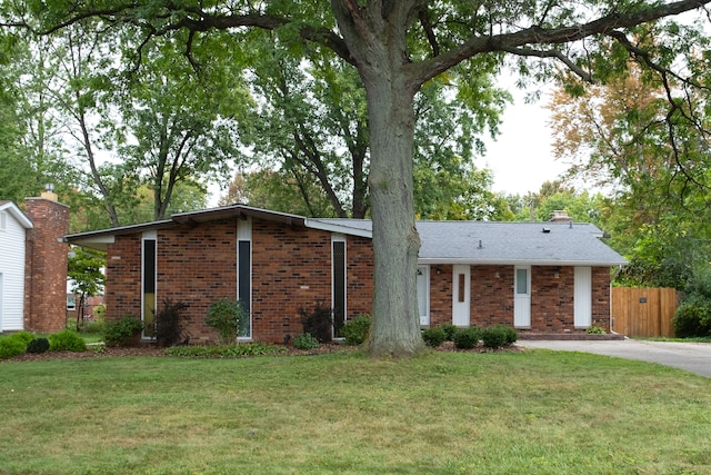 view of front of house featuring fence, a front lawn, a chimney, and brick siding