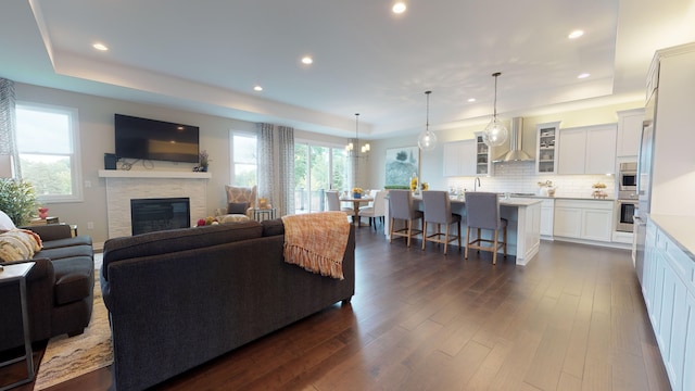 living room with dark hardwood / wood-style flooring, plenty of natural light, and a raised ceiling